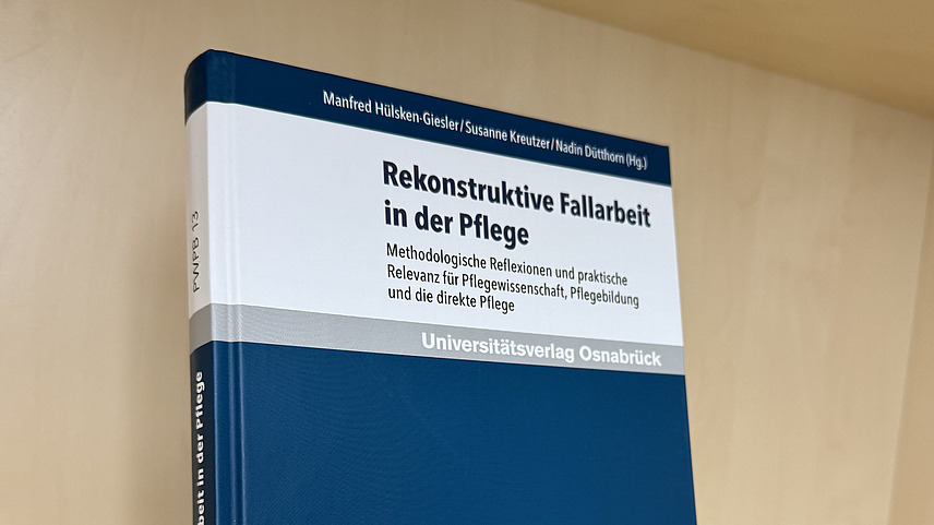 Ein Fachbuch von Manfred H&uuml;lsken-Giesler, Susanne Kreutzer und Nadin D&uuml;tthorn mit dem Titel "Rekonstruktive Fallarbeit in der Pflege. Methodologische Reflexion und praktische Relevanz f&uuml;r Pflegewissenschaft, Pflegebildung und die direkte Pflege" steht in einem Regal.