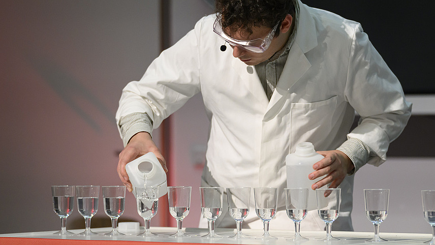 Person in wei&szlig;em Kittel unternimmt ein chemisches Experiment