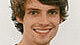 young man with dark hair smiles into the camera
