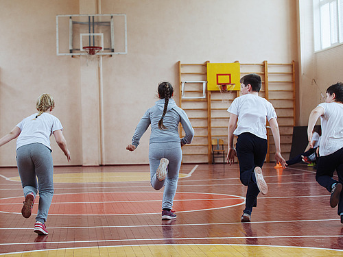 Four pupils run through a gym. 