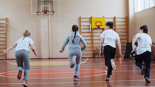 Four pupils run through a gym. 