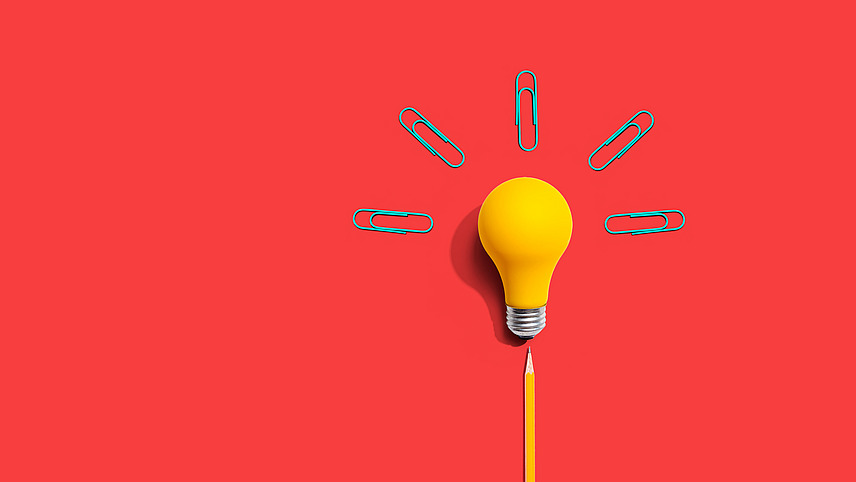 gelbe Gl&uuml;hbirne vor rotem Hintergrund