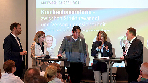 Several people speak in front of a screen during a panel discussion