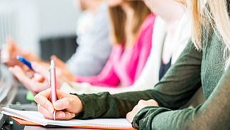 Mehrere Personen sitzen nebeneinander und schreiben