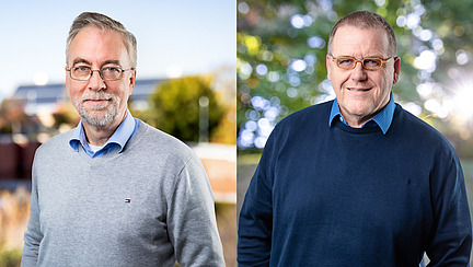 Zwei M&auml;nner l&auml;cheln in die Kamera.