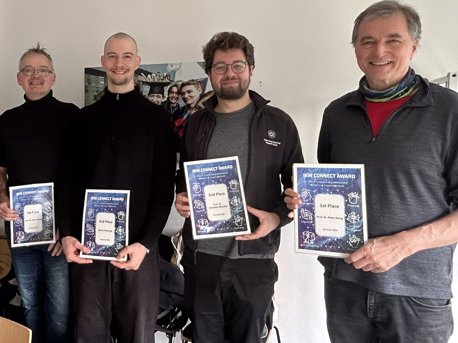Four men stand side by side, holding certificates in their hands. 