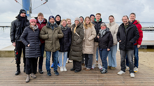 Das Kollegium steht zusammen auf einem Steg vor dem D&uuml;mmer See.