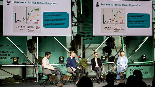 Panelists sit in a semicircle on the stage of the Impact Festival