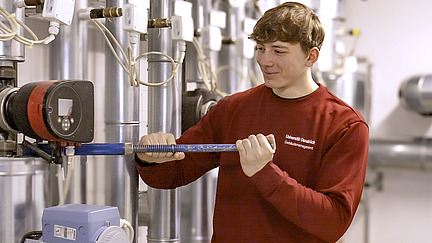 Ein Auszubildender arbeitet mit einer gro&szlig;en Zange an einem Rohr