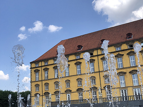 Der Springbrunnen hinter dem Schloss vor einem blauen Himmel.