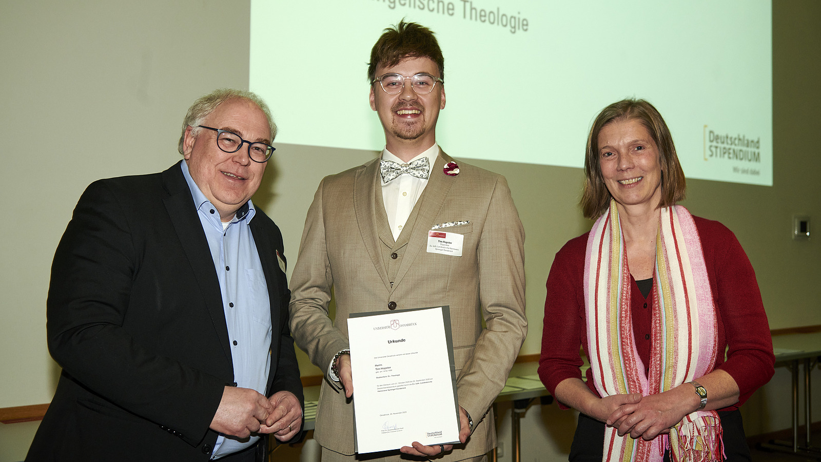 Mehrere Personen auf Bühne bei Urkundenübergabe