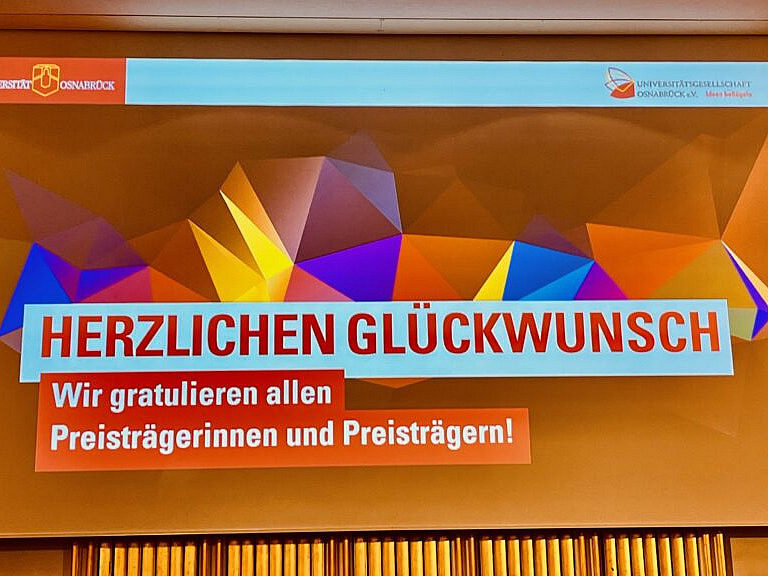 Eine bunte Präsentation, die den Preisgewinnern Glückwünsche ausspricht.
