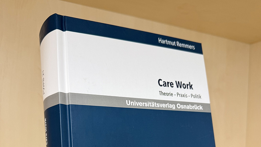 Ein Fachbuch von Hartmut Remmers mit dem Titel "Care Work. Theorie - Praxis - Politik."" steht in einem Regal.