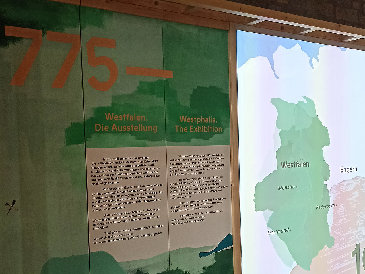 Das Bild zeigt eine grüne Infotafel mit der Jahreszahl 775, rechts daneben ist eine Karte von Westfalen.