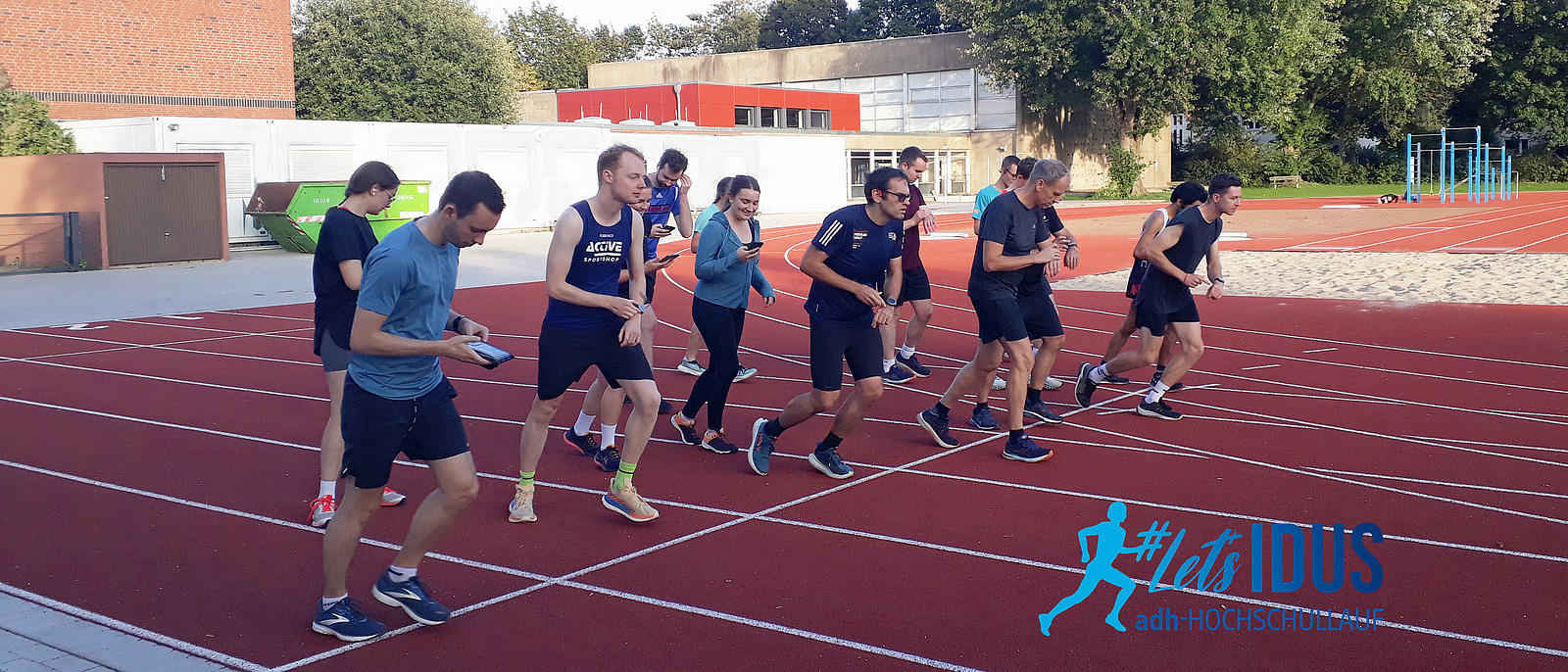 Eine Gruppe von Läuferinnen und Läufern an der Startlinie einer Laufbahn