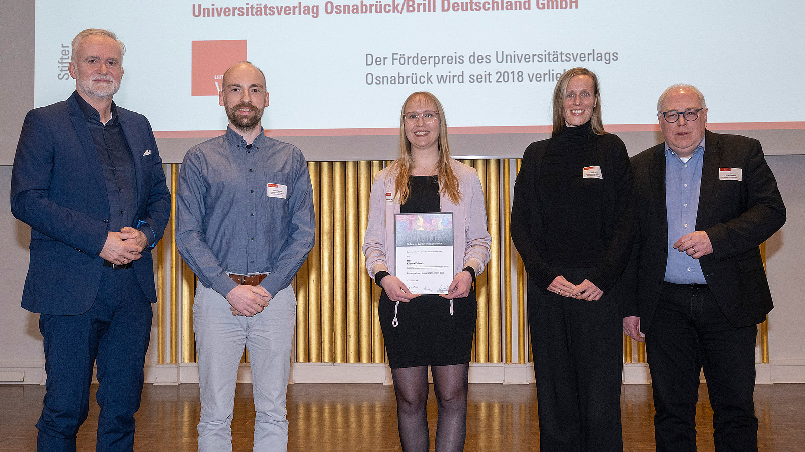 Preisträger, Stifter und der Vizepräsident stehen zusammen auf der Bühne und lächeln in die Kamera