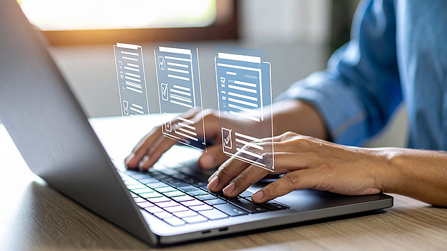 Ein Mensch tippt auf einem Laptop, wobei Datenvisualisierungen &uuml;ber dem Bildschirm schweben.