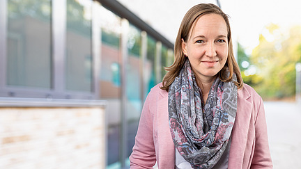 Caroline Barisch steht l&auml;chelnd vor einem Geb&auml;ude