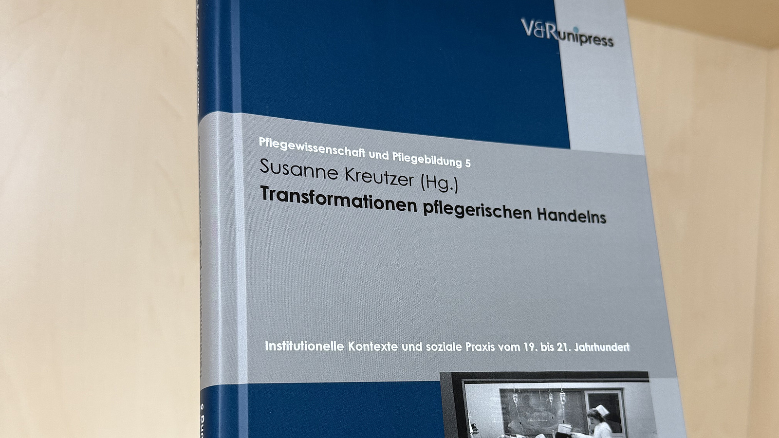 Ein Fachbuch von Susanne Kreutzer mit dem Titel "Transformationen pflegerischen Handelns" steht in einem Regal.