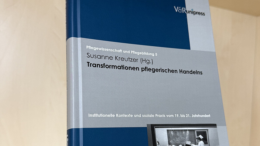 Ein Fachbuch von Susanne Kreutzer mit dem Titel "Transformationen pflegerischen Handelns" steht in einem Regal.