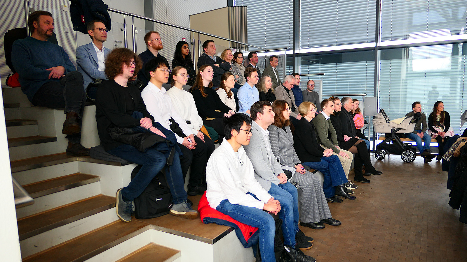 Viele Personen sitzen in Stuhlreihen.