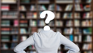 A person is standing in front of a bookshelf. The head is replaced by a question mark.