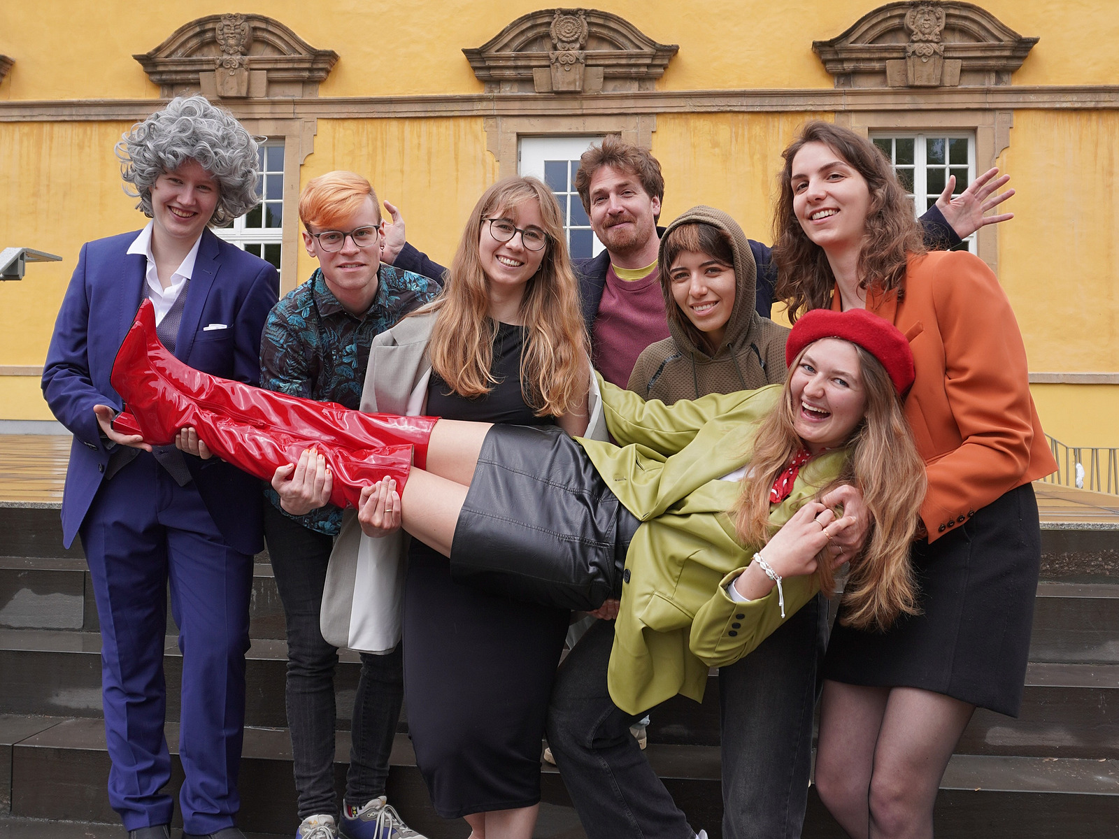 A group of actors laugh into the camera.