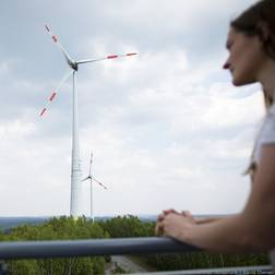 Zwei Windräder auf dem Osnabrücker Piesberg, im Vordergrund ist unscharf eine Frau zu sehen