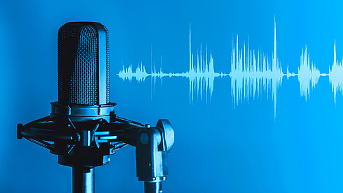 Microphone in front of a neutral background from which sound waves emanate