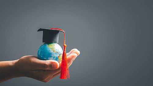 One hand holds a tiny globe. 