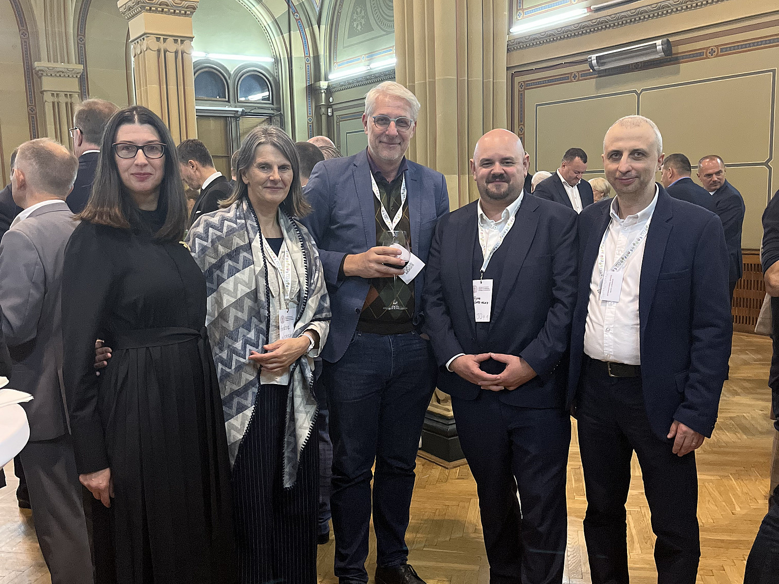 Mehrere Männer und Frauen stehen in einer Universität zusammen und blicken in die Kamera.