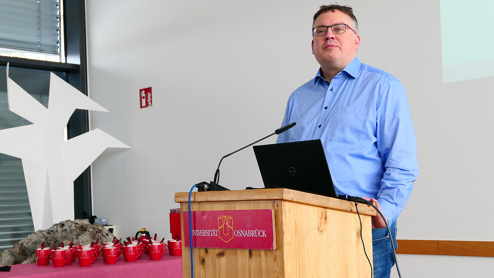 Ein Mann steht an einem Rednerpult der Universit&auml;t Osnabr&uuml;ck.