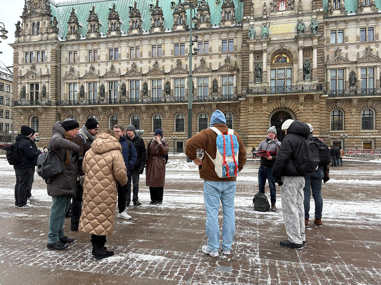 Das Bild zeigt eine Gruppe Menschen vor dem Hamburger Rathaus.