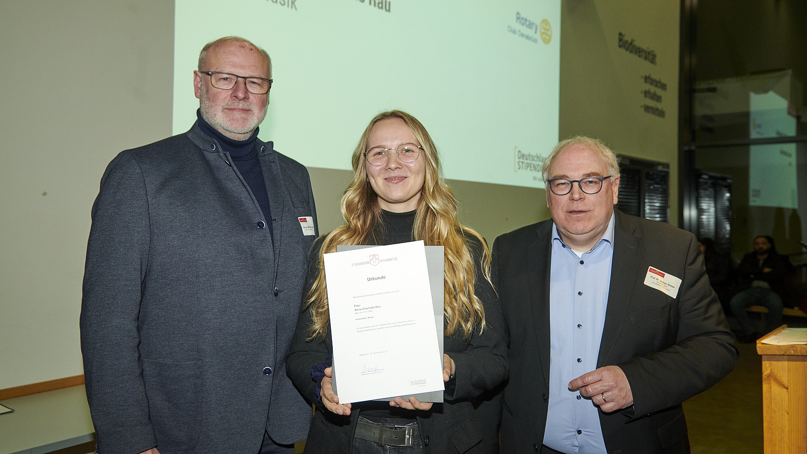 Mehrere Personen auf Bühne bei Urkundenübergabe