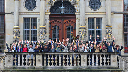 A group of international students stand in front of the entrance to Bremen City Hall. They all seem relaxed.