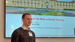 Gerrit Wittke, im Hintergrund Folie seines Vortrages, auf der das Universitätsgebäude Osnabarück, gelbes Schloss, sowie das Thema seines Vortrages abgebildet sind.