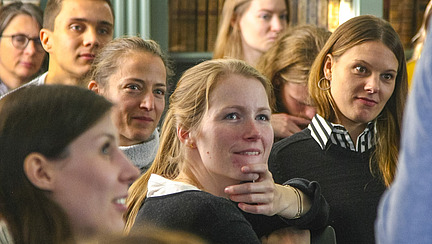 A crowd of people, some looking happy