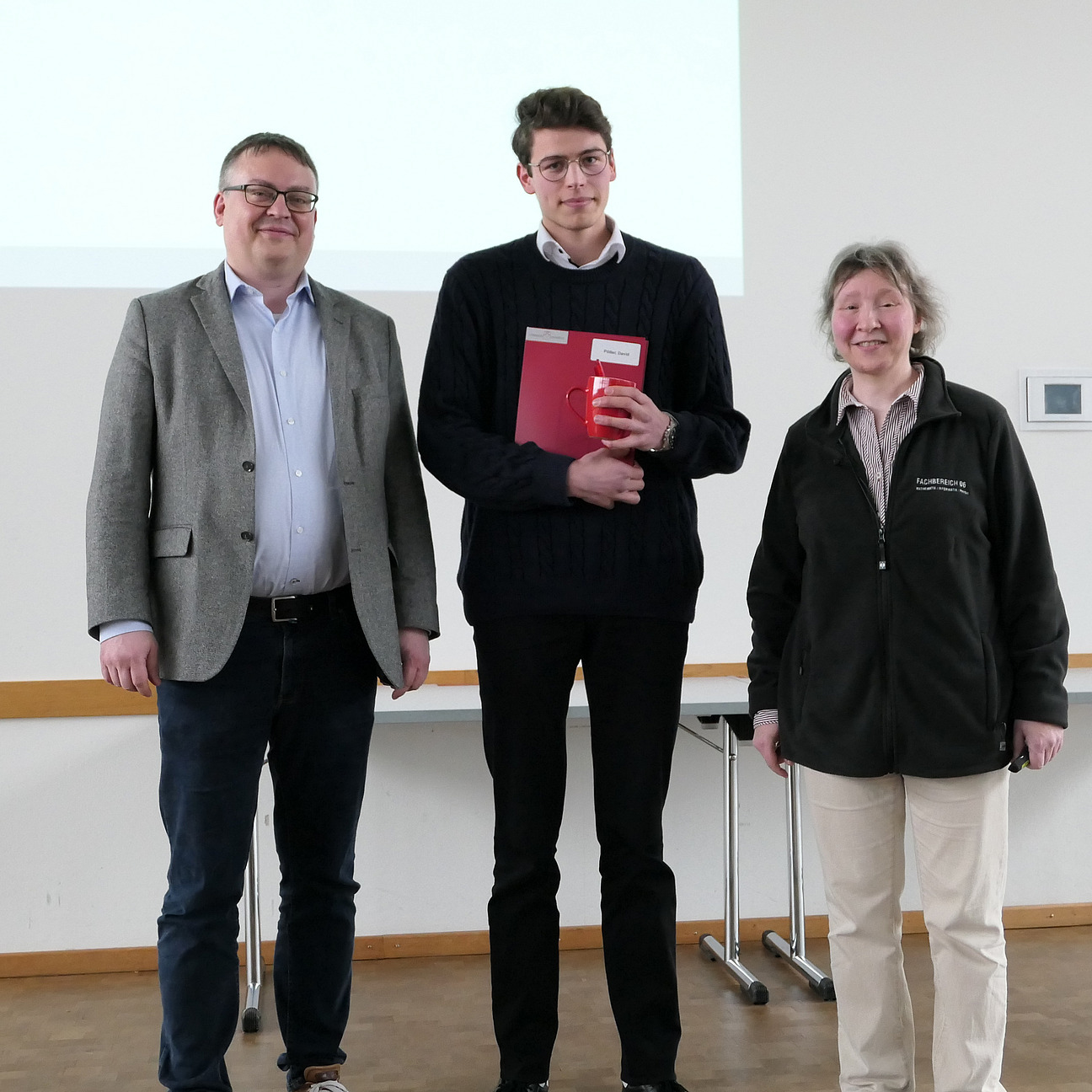 A graduate stands between the dean and the dean of studies.