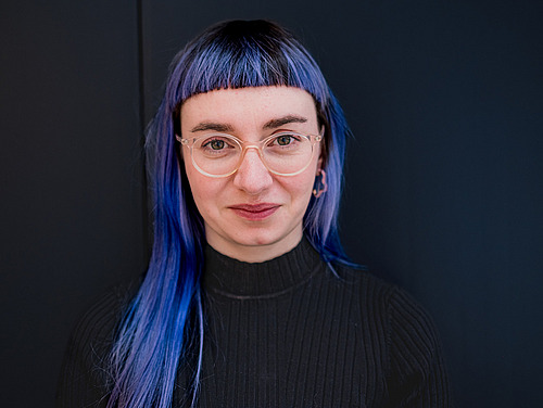 A woman looks into a camera. 