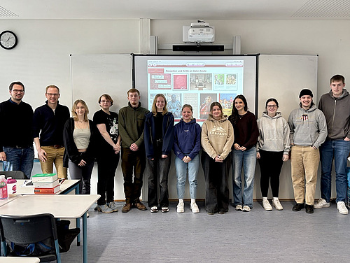 Michael Neumann mit den Sch&uuml;lerinnen und Sch&uuml;lern des Geschichts-LKs im Klassenraum vor der Tafel.