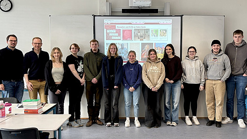 Michael Neumann mit den Sch&uuml;lerinnen und Sch&uuml;lern des Geschichts-LKs im Klassenraum vor der Tafel.