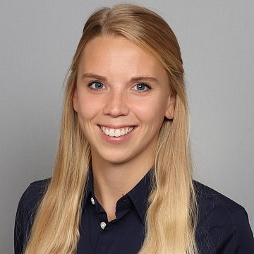 Frau lächelt vor grauem Hintergrund.