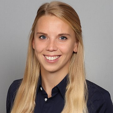 Frau lächelt vor grauem Hintergrund.