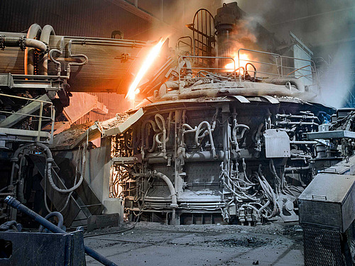 Innenansicht eines aktiven Stahlwerks mit einem großen Ofen in der Mitte