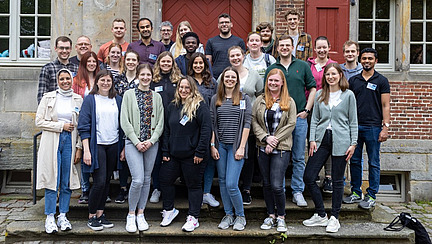 A group of about 30 people stand on a staircase and smile into the camera.