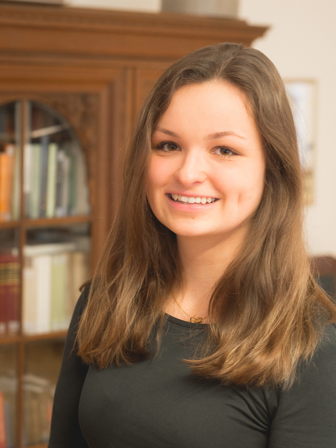 Annalena Schwettlick, studentische Hilfskraft. Sie hat lange dunkle Haare, lächelt und tärgt ein dunkles Shirt. 