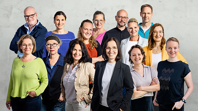 The team stands together in a group, all looking at the camera.