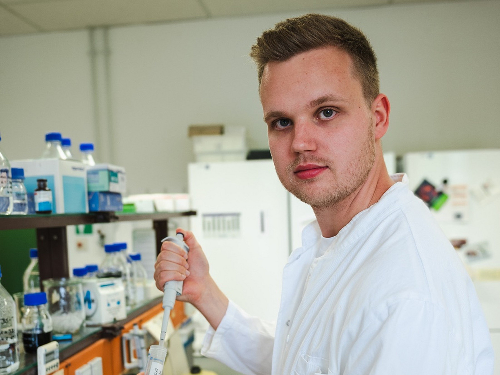 Ein Mann steht im Labor und h&auml;lt eine Pipette in der Hand.