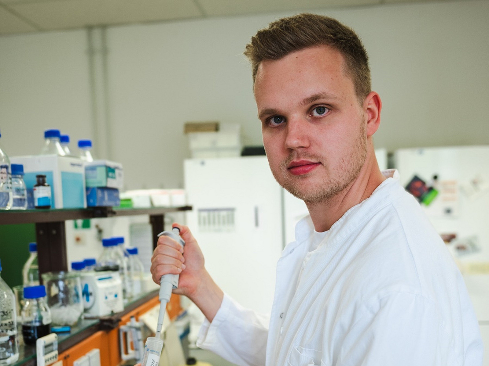A man stands in the laboratory holding a pipette
