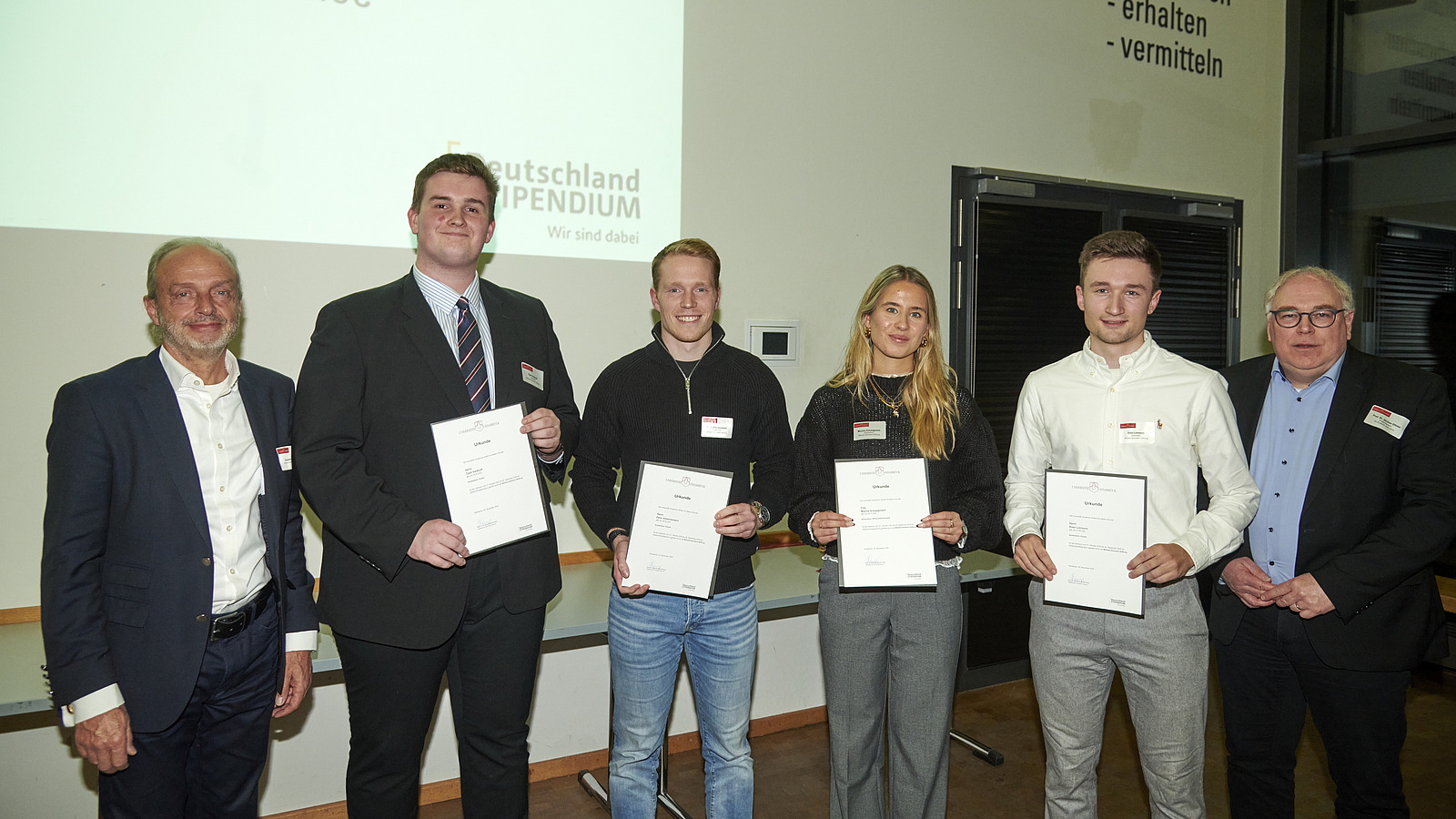 Mehrere Personen auf Bühne bei Urkundenübergabe